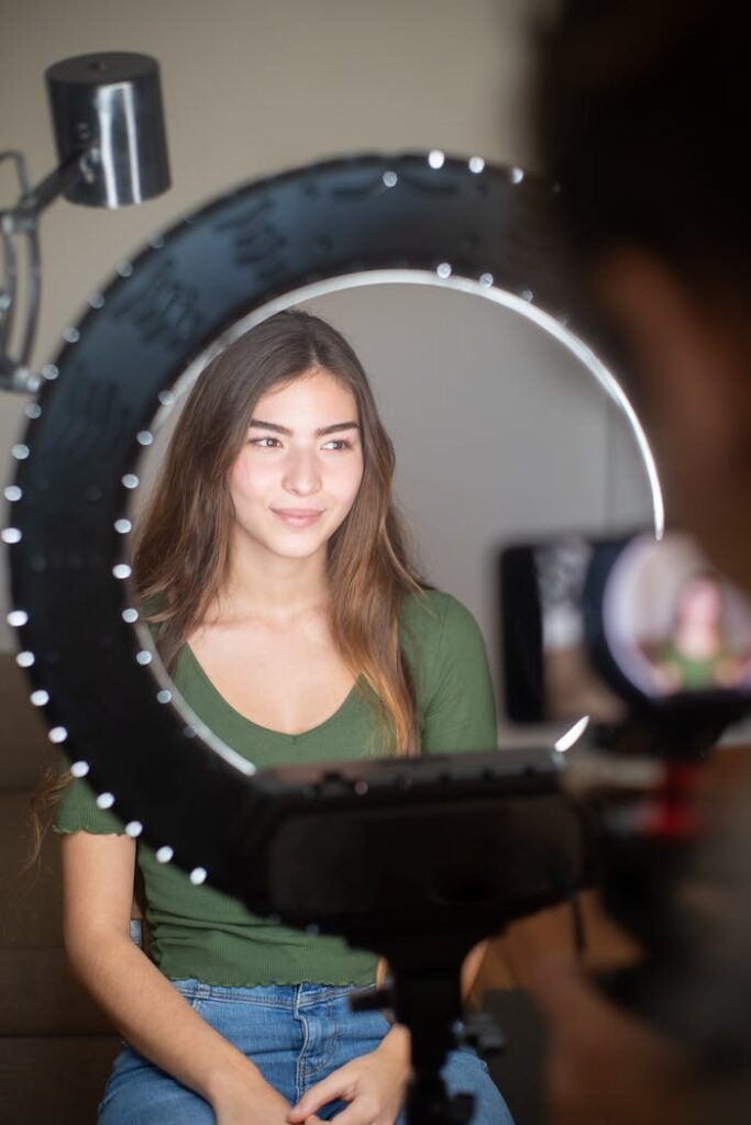 Portrait of a woman streaming online with professional ring light and camera setup.